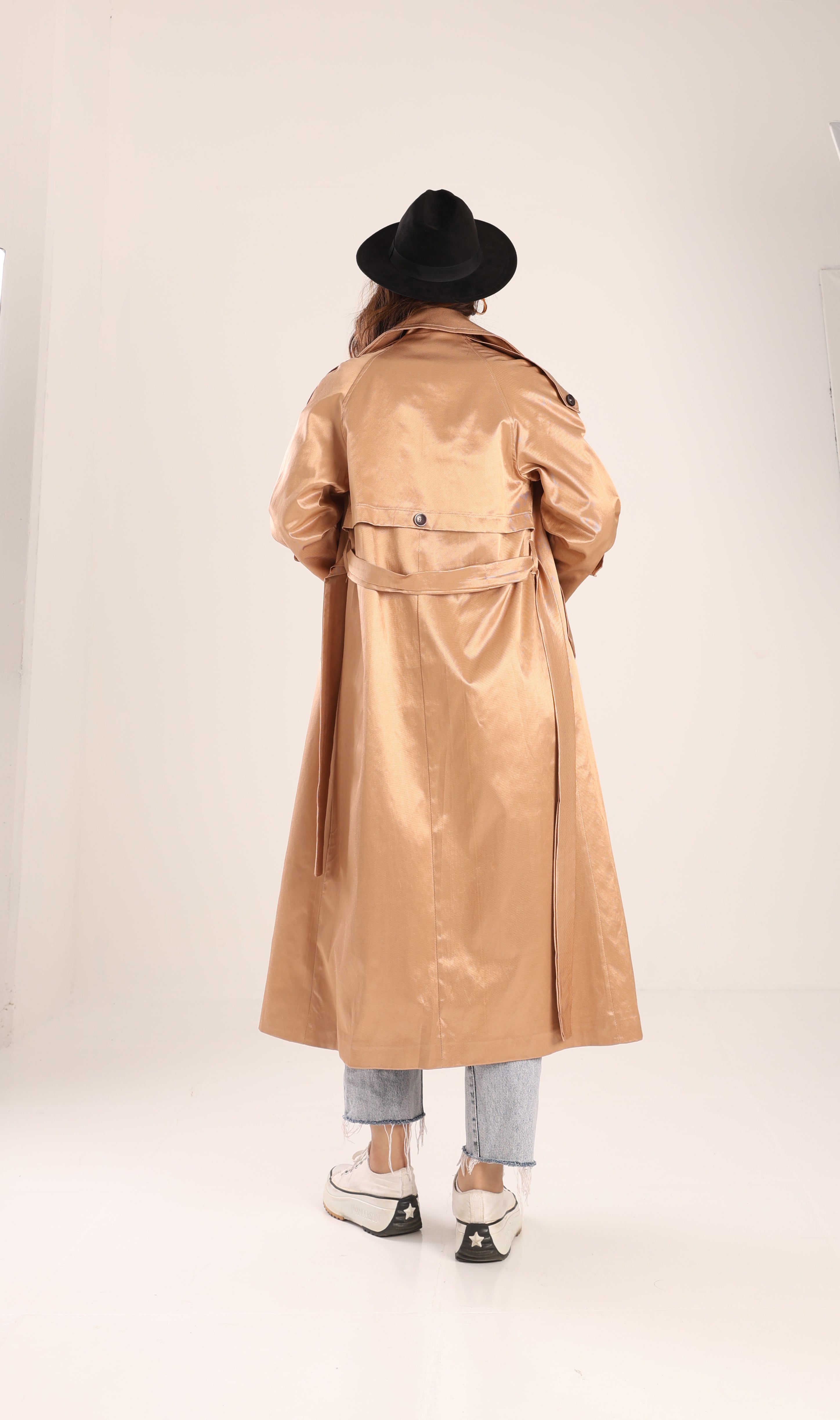 Person wearing a beige trench coat and black hat on a white background