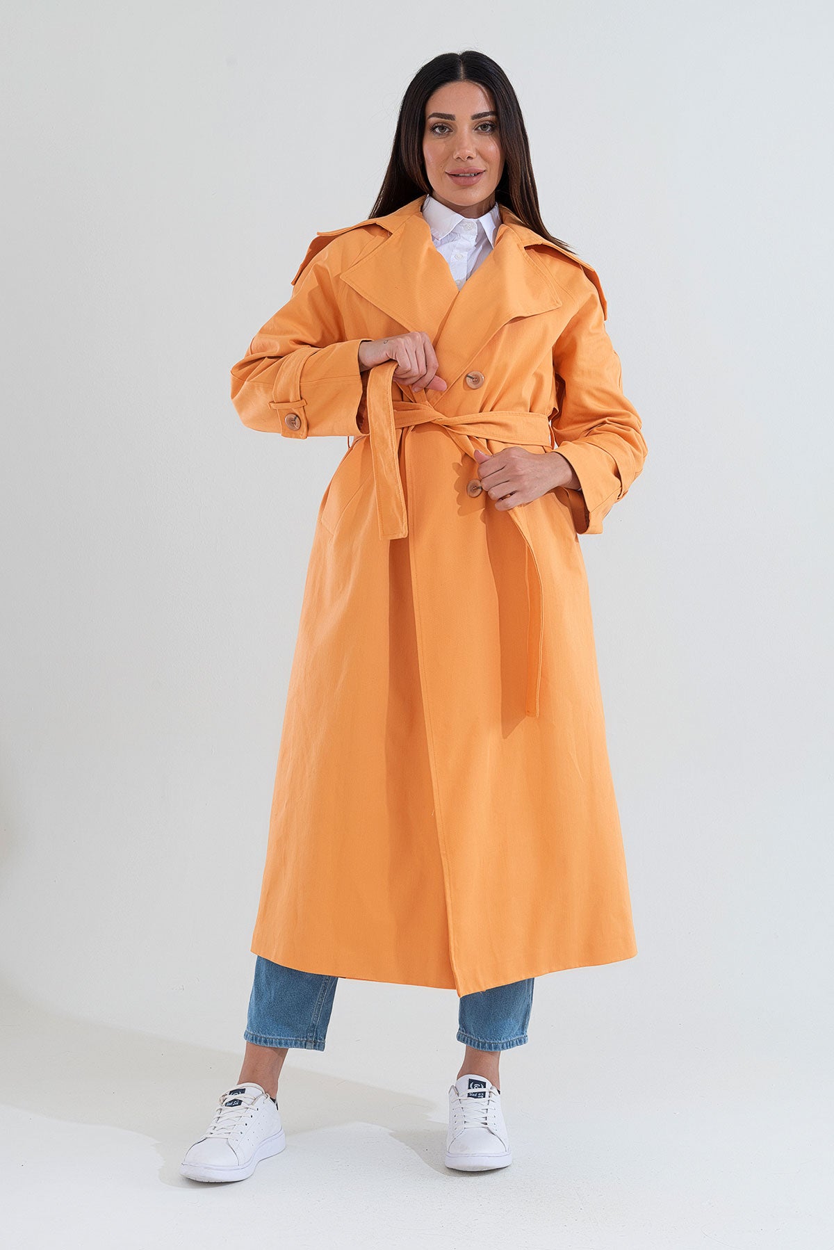 Woman wearing an orange trench coat on a white background