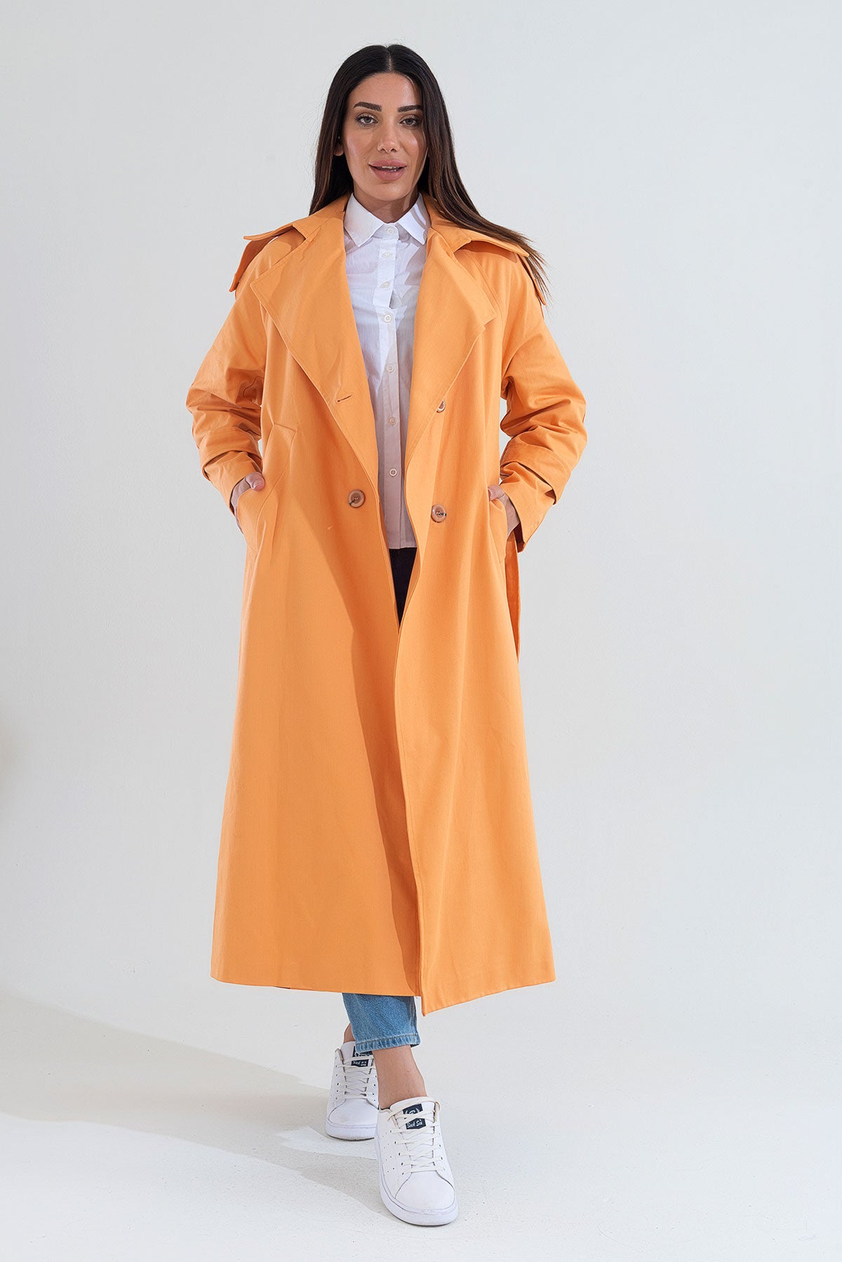 Woman wearing an orange trench coat on a white background