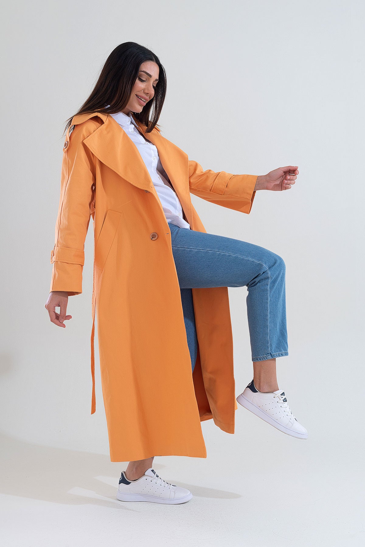 Woman wearing an orange trench coat on a white background