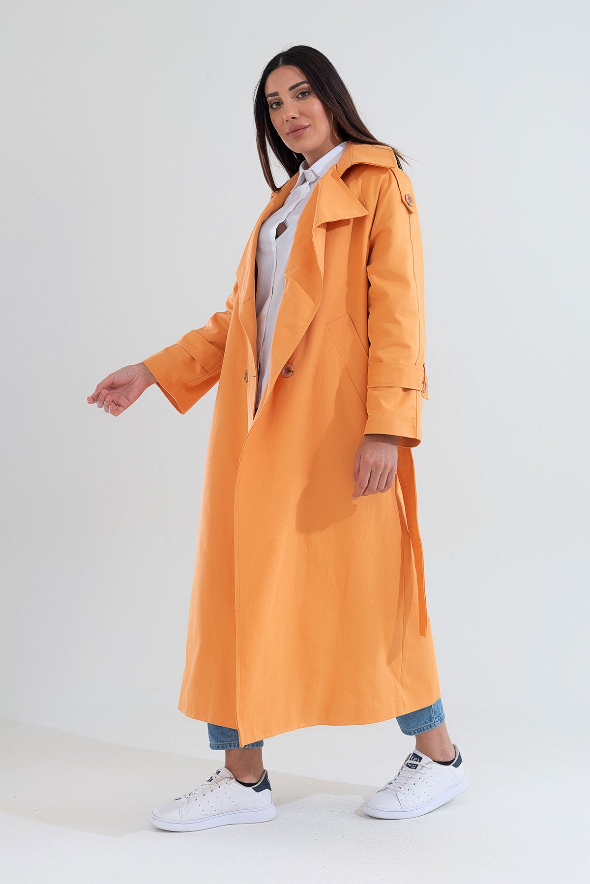 Woman wearing an orange trench coat on a white background