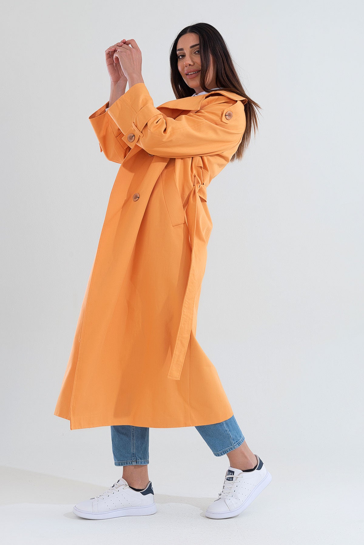 Woman wearing an orange trench coat on a white background