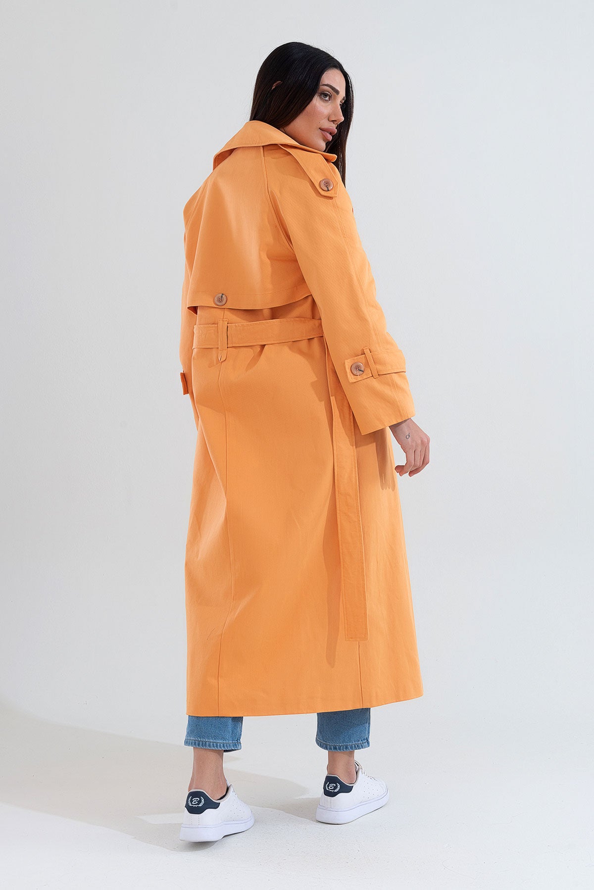 Woman wearing an orange trench coat on a white background