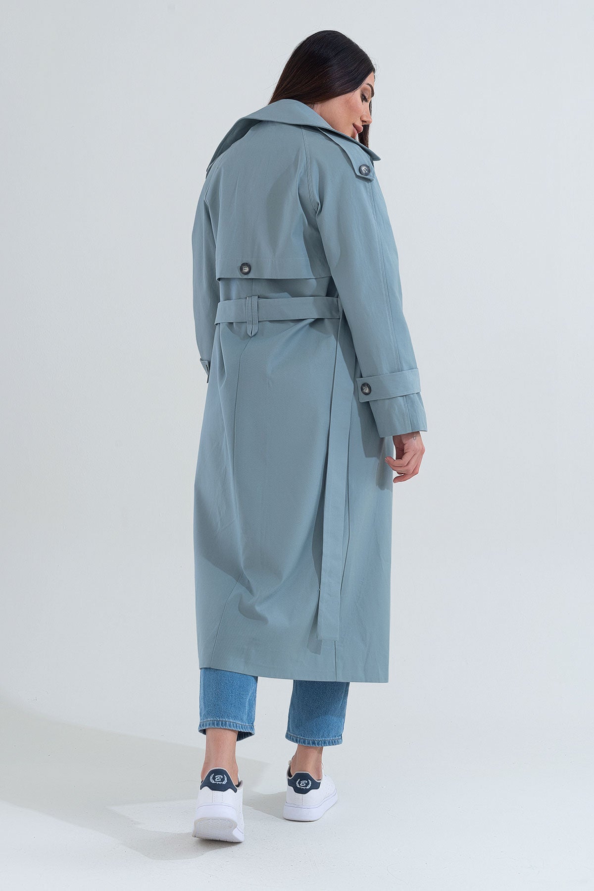 Person wearing a long light blue coat on a white background