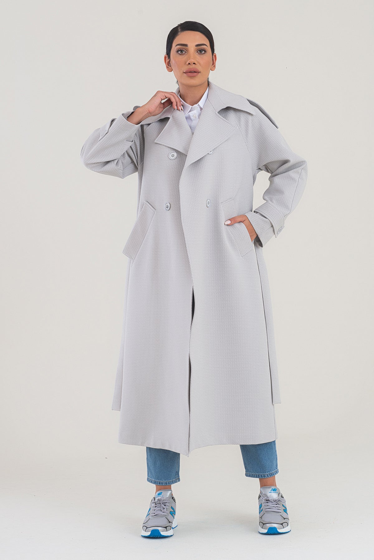 Woman wearing a long gray coat on a white background