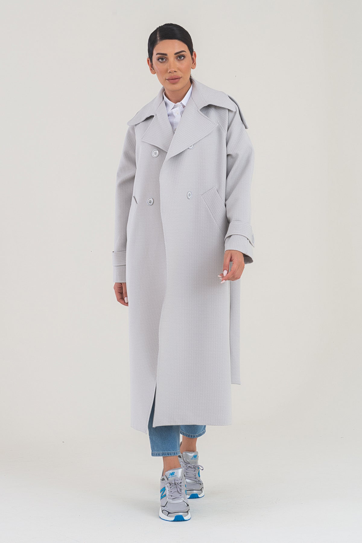 Woman wearing a light gray trench coat on a white background