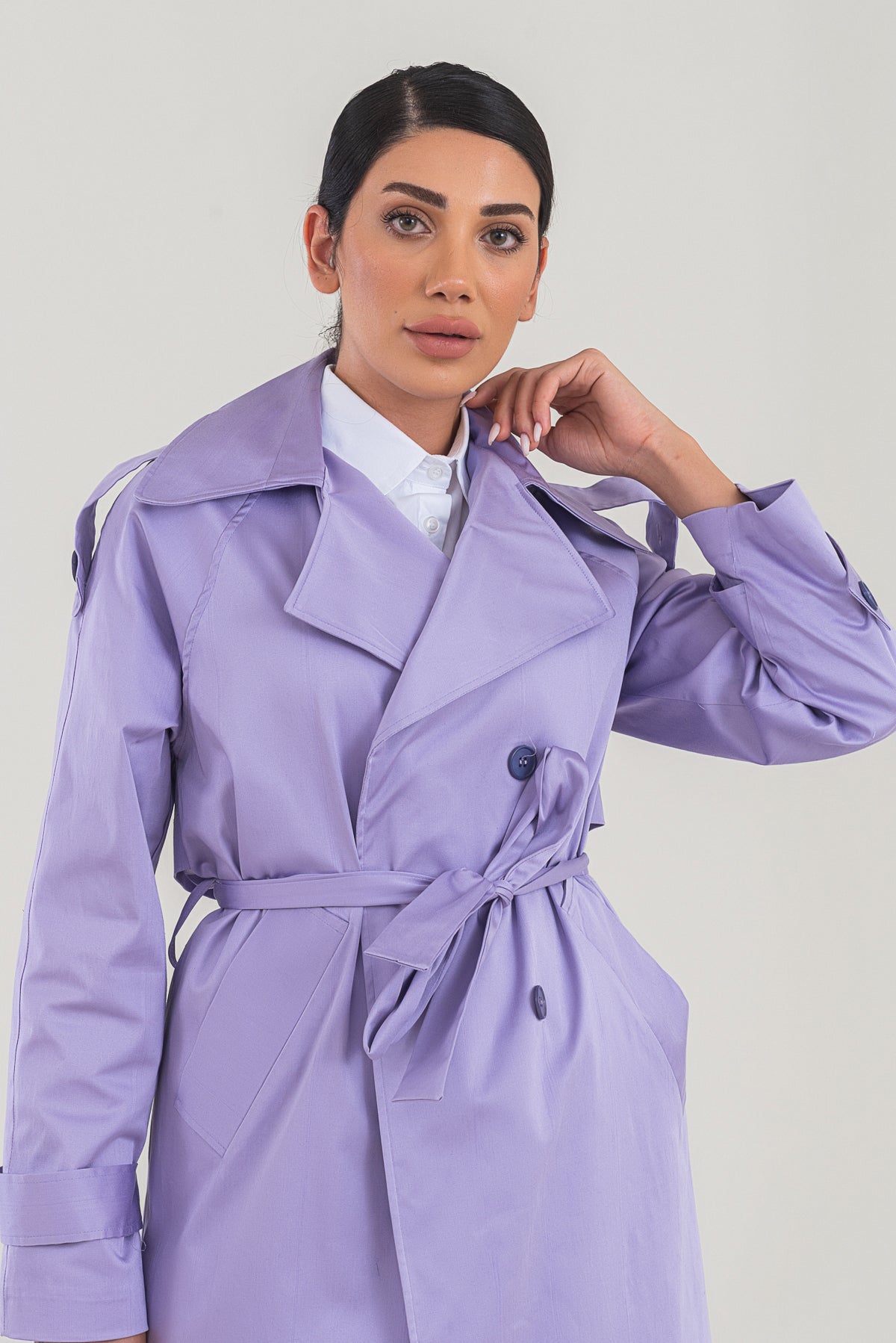 Woman wearing a purple trench coat against a plain background