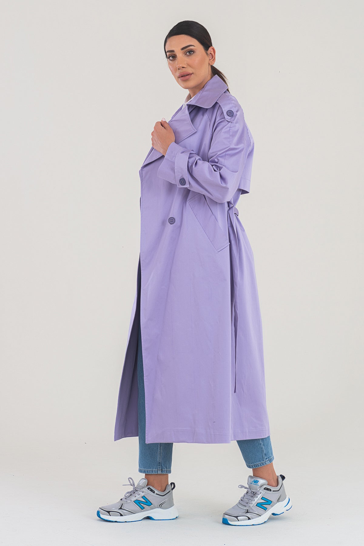 Woman wearing a long lavender coat on a white background