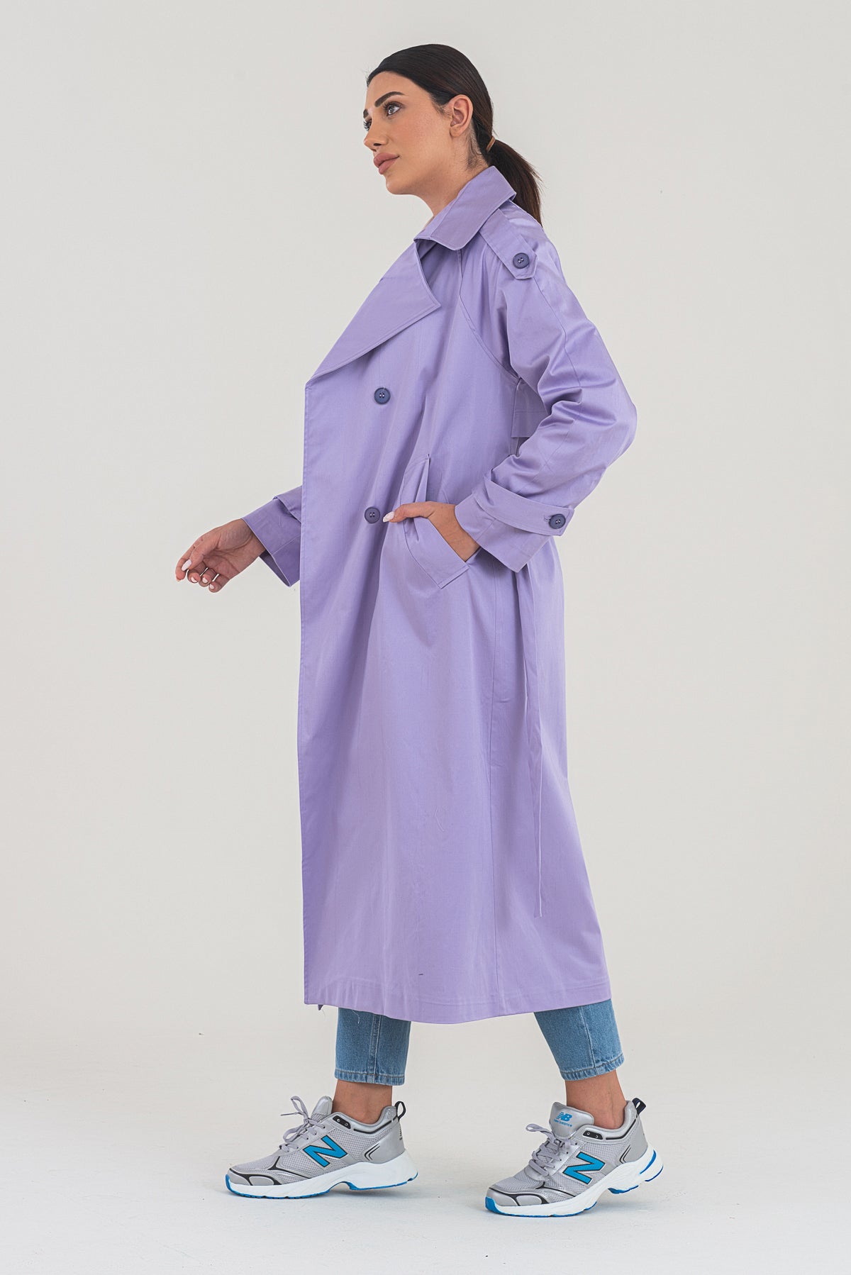 Woman wearing a long purple coat on a white background