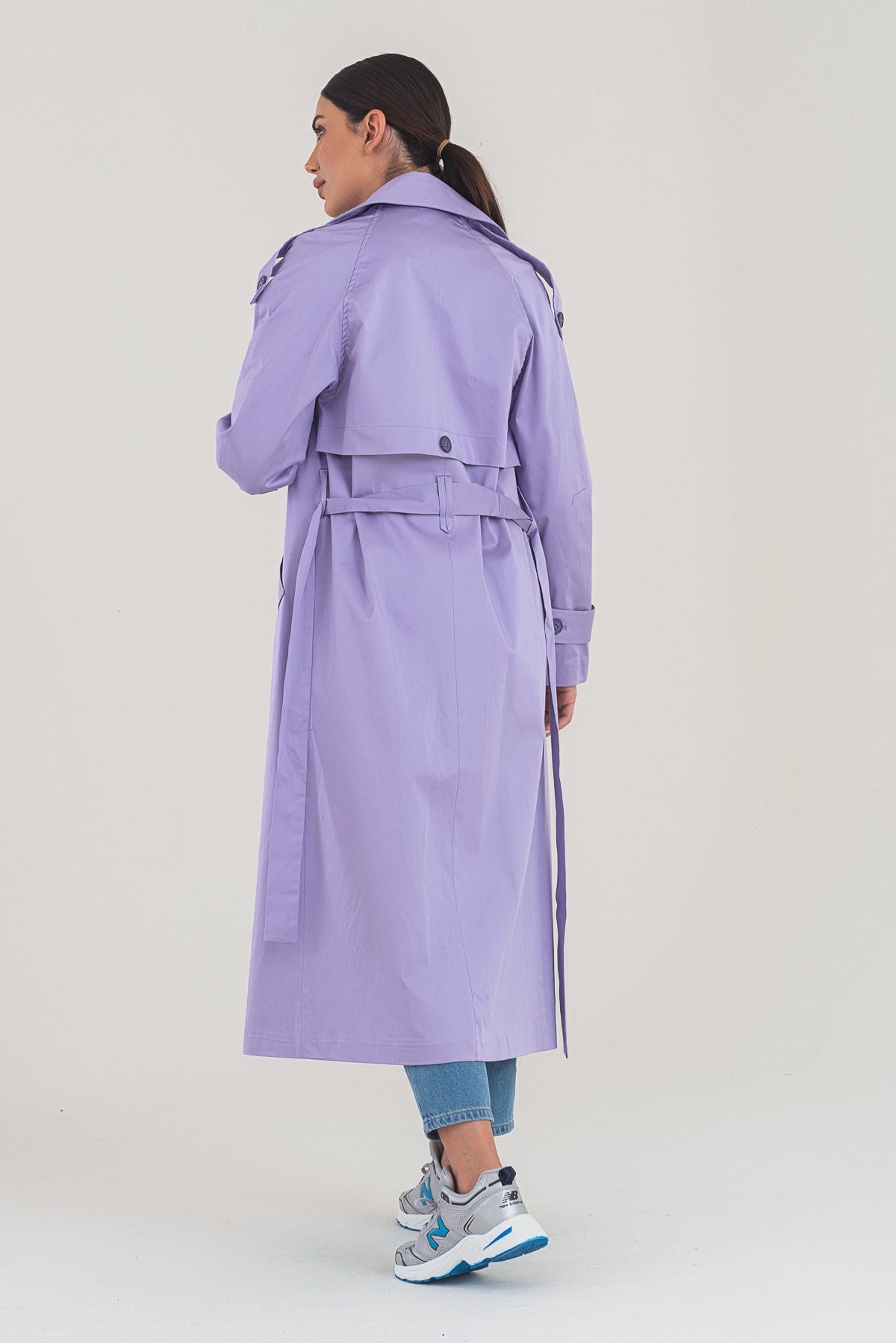 Person wearing a purple trench coat on a plain background